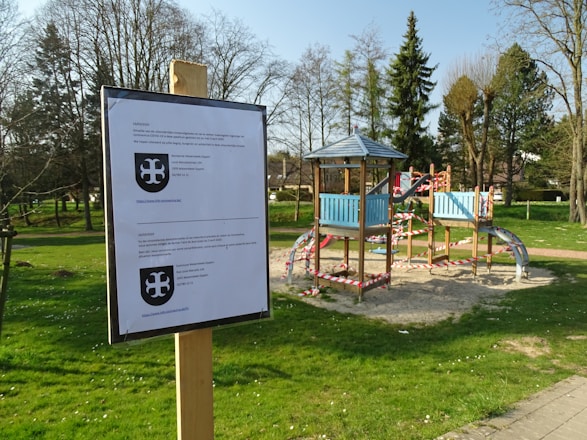 A playground safety consultant inspecting equipment with a clipboard on a sunny day.