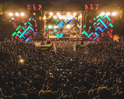 Evening shot of a road show stage lit up with colorful lights and an engaged crowd.