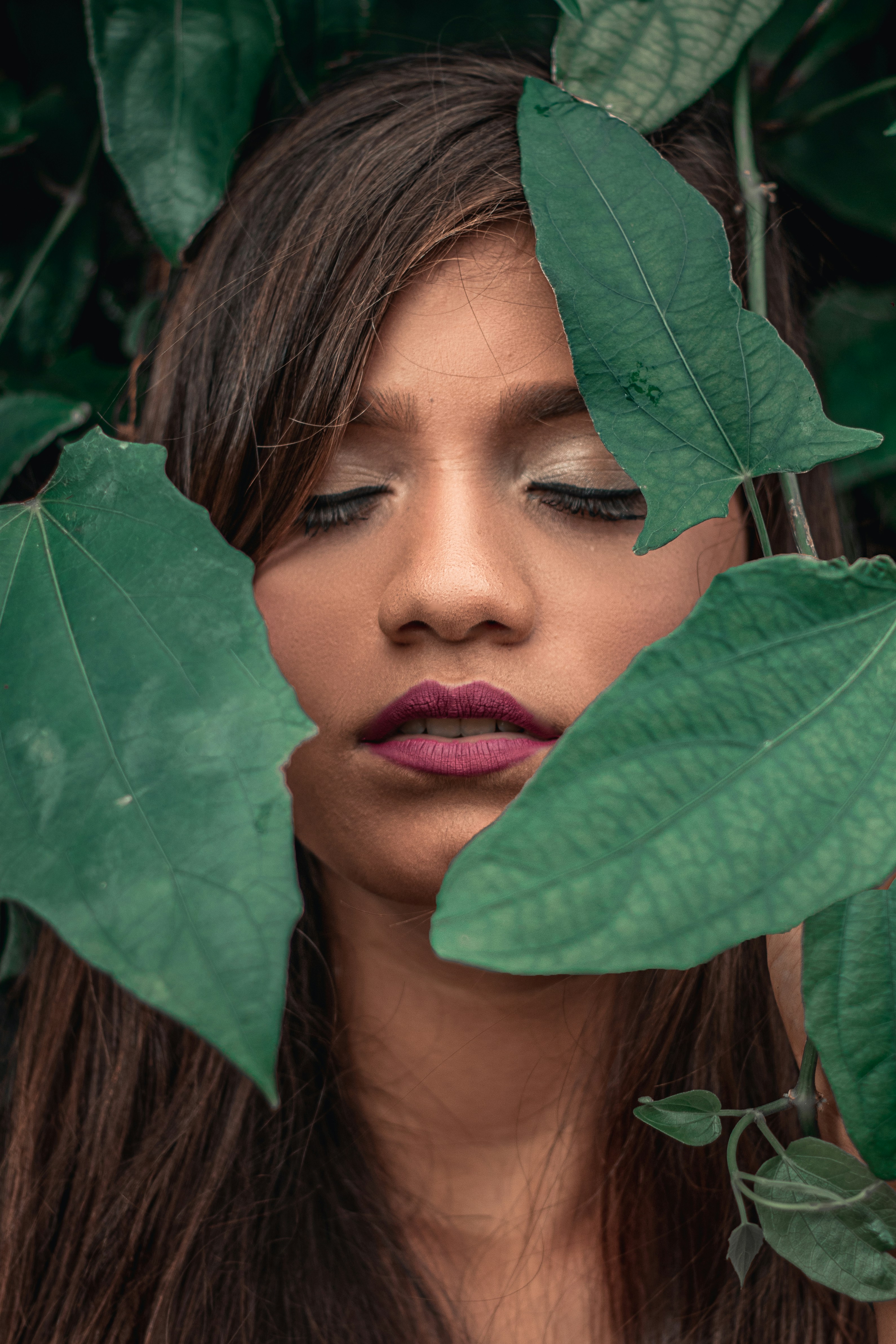woman hiding behind green leaves