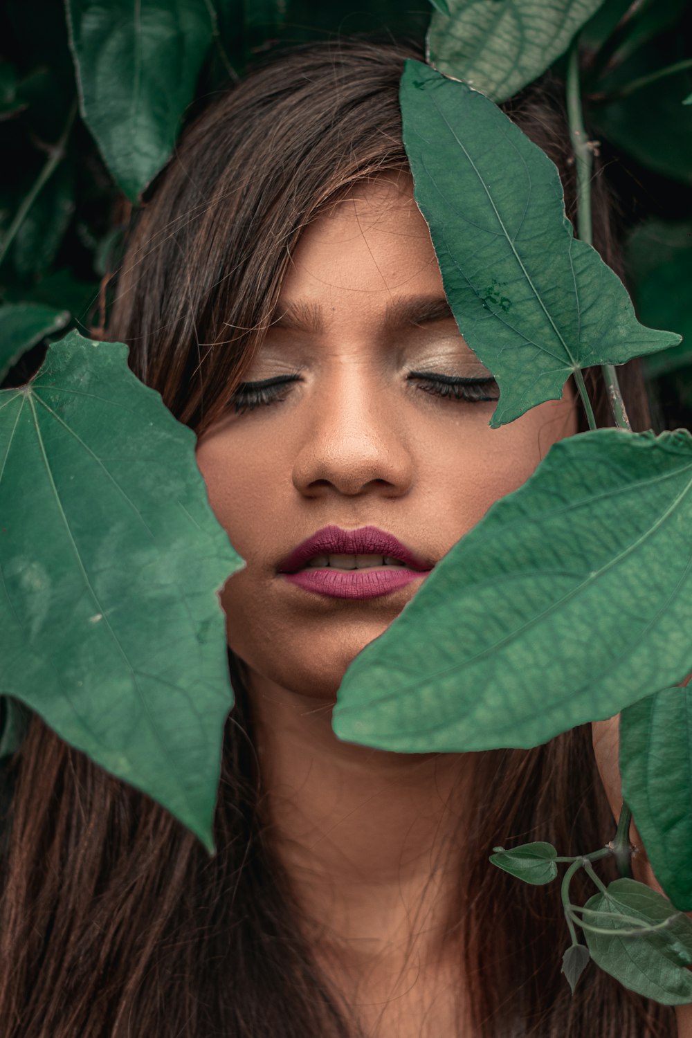 woman hiding behind green leaves