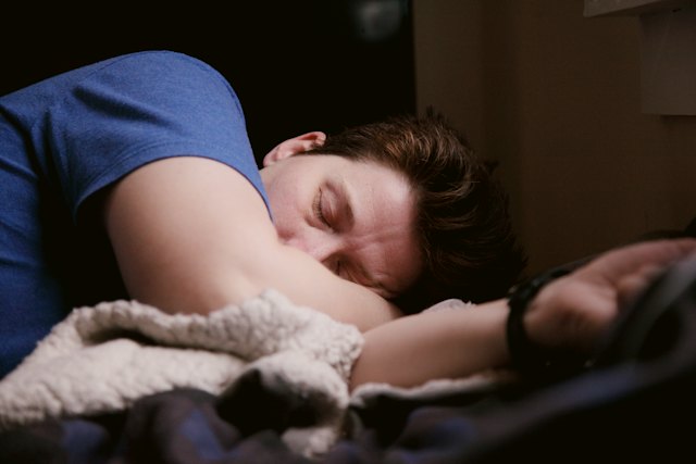 Mann liegt krank im Bett und schläft