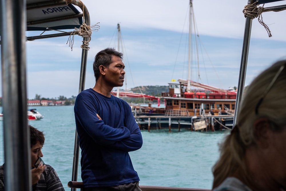 man in blue crew neck long sleeve shirt standing on dock during daytime