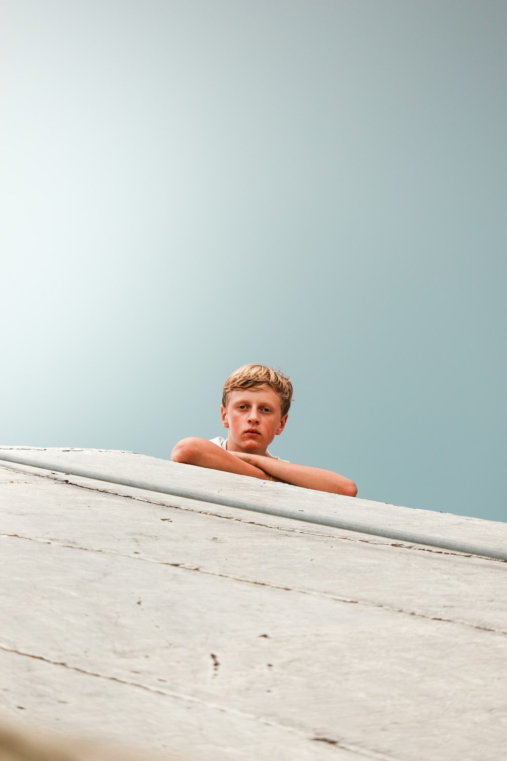 昼間、白い砂浜に横たわるトップレスの少年