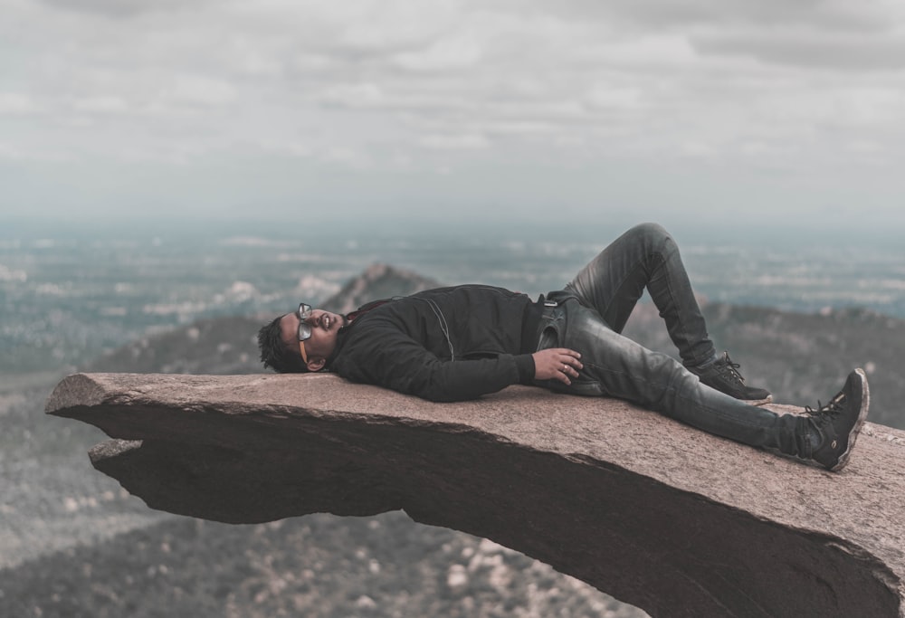 a man laying on top of a large rock