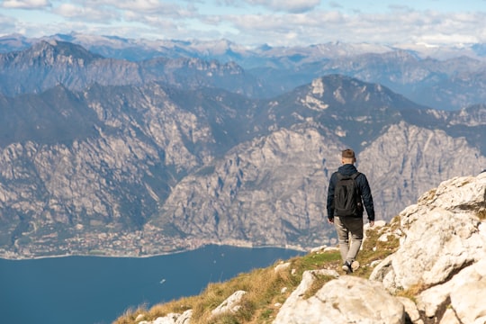 man in black jacket standing on rock mountain during daytime in Lake Garda Italy