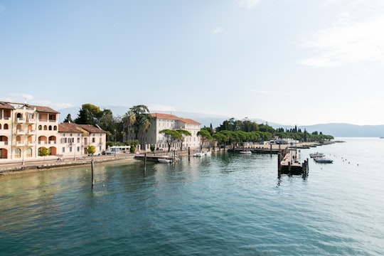white and brown concrete building beside body of water during daytime in Lago di Garda Italy