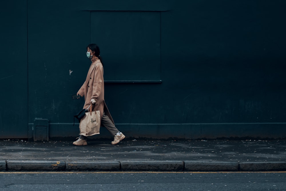 uomo in cappotto marrone in piedi accanto al muro blu