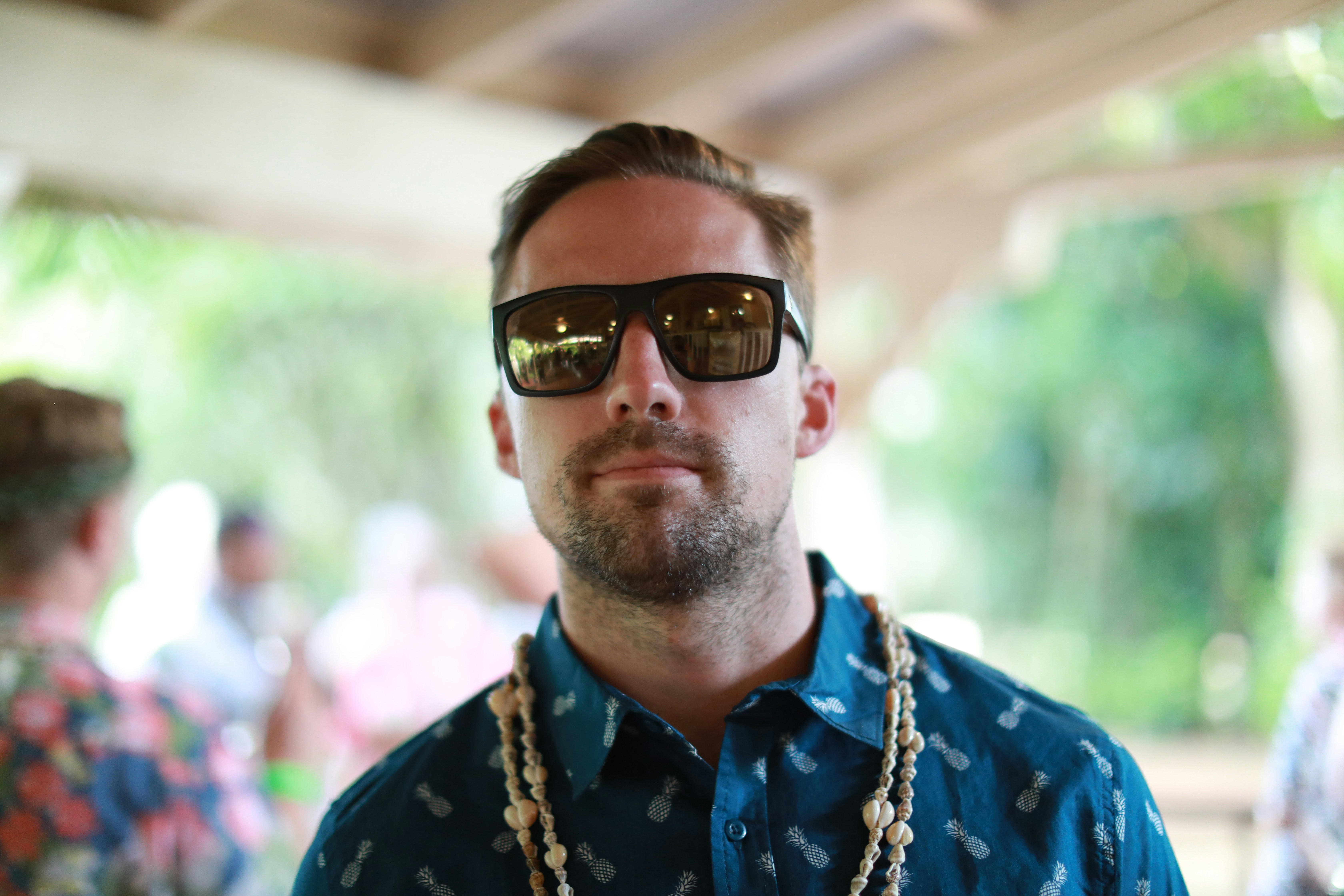 man in blue and yellow floral button up shirt wearing black sunglasses, Young man at a luau in Hawaii. 