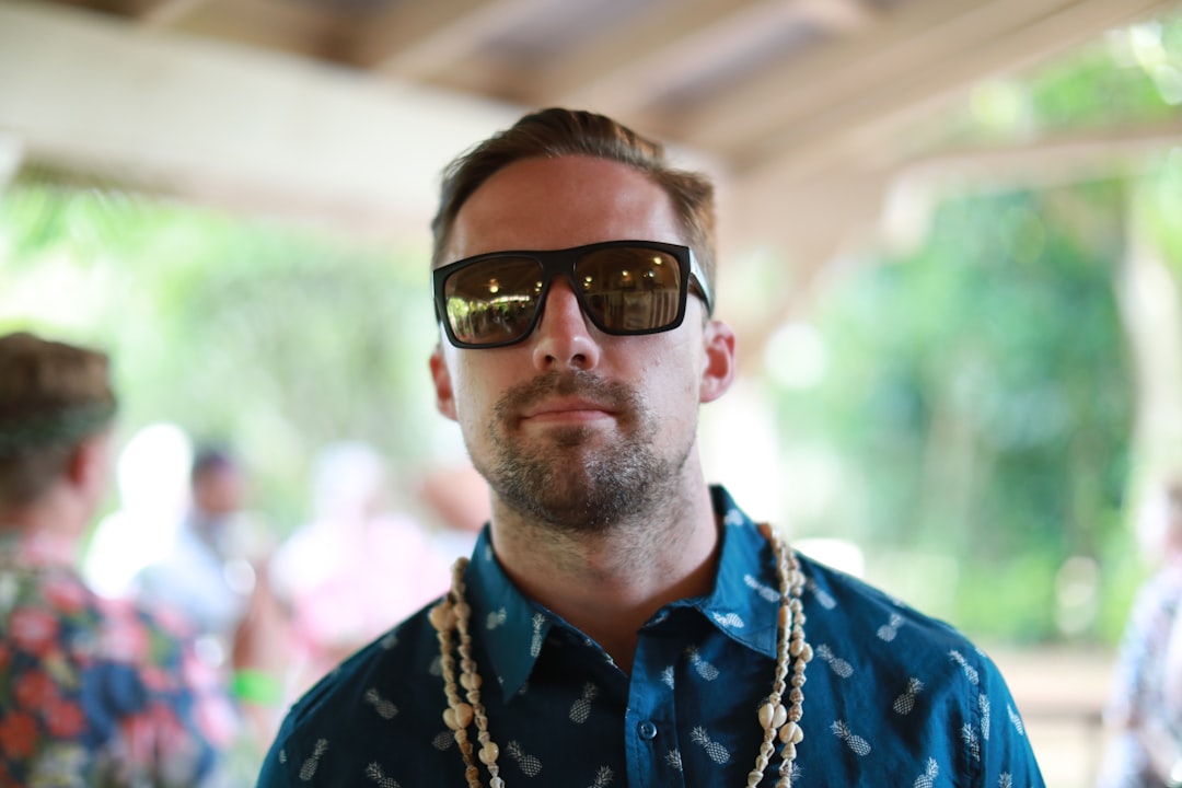 man in blue and yellow floral button up shirt wearing black sunglasses, Young man at a luau in Hawaii.