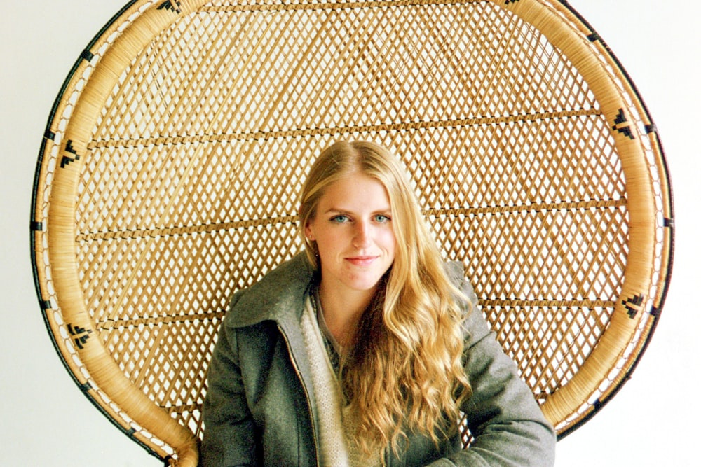 woman in gray coat sitting on brown wooden chair