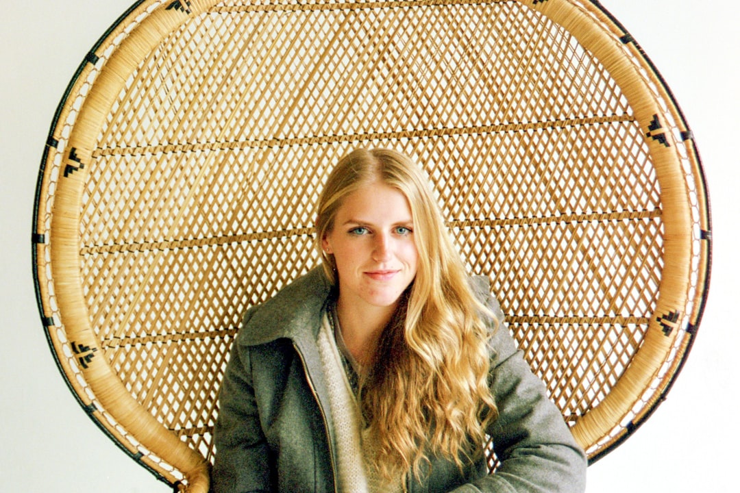 woman in gray coat sitting on brown wooden chair