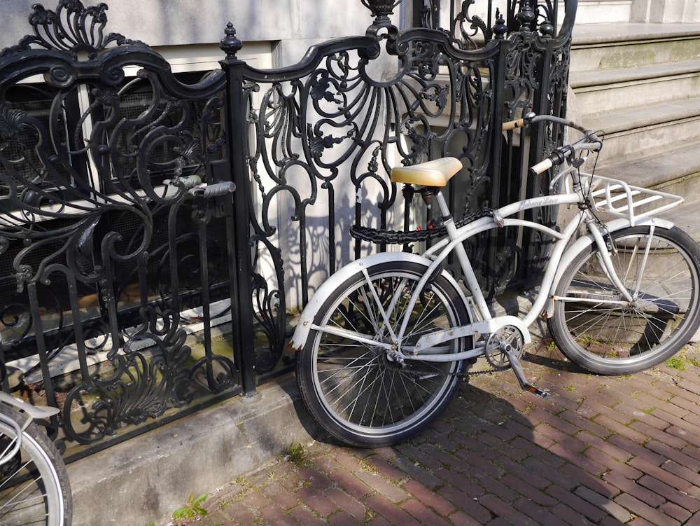 black and white city bike parked beside black metal fence