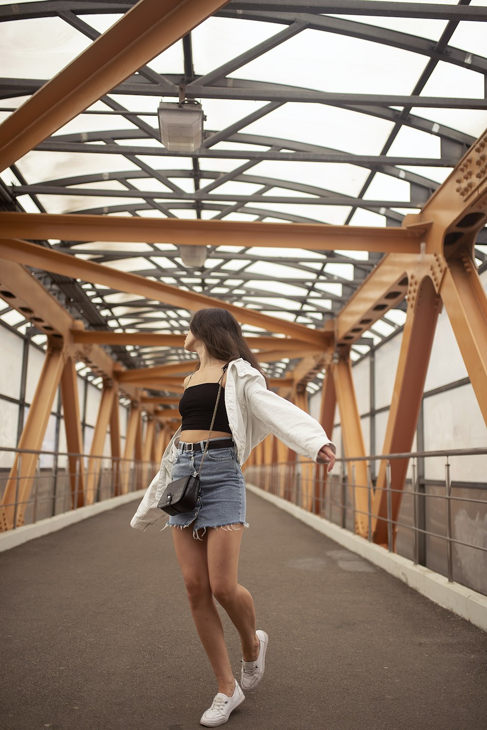 Frau in weißem Langarmhemd und blauen Jeansshorts auf grauem Betonboden