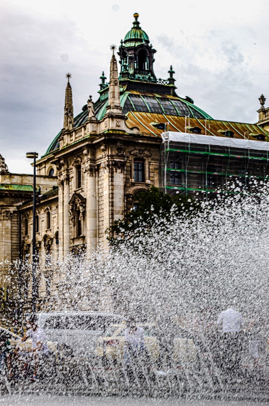 water fountain in front of green and brown building in Justizpalast Germany