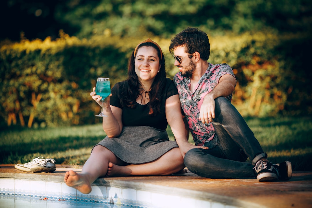 man and woman sitting on brown wooden bench during daytime