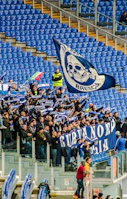 Fans in blue and white cheering passionately in the stadium stands.