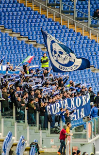 Excited fans waving scarves and flags in the stands.