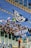 A group of enthusiastic sports fans are gathered in a stadium, holding flags, banners, and scarves that display blue and white colors and symbols. The stands are mostly empty except for this section, and the fans appear to be cheering and waving their items energetically.