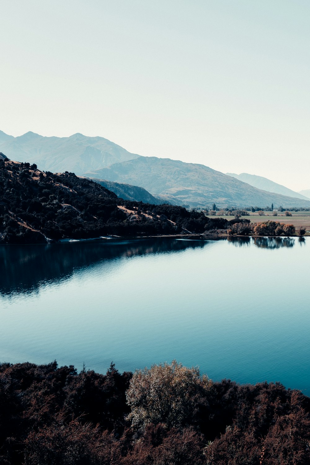 lake surrounded by trees and mountains during daytime