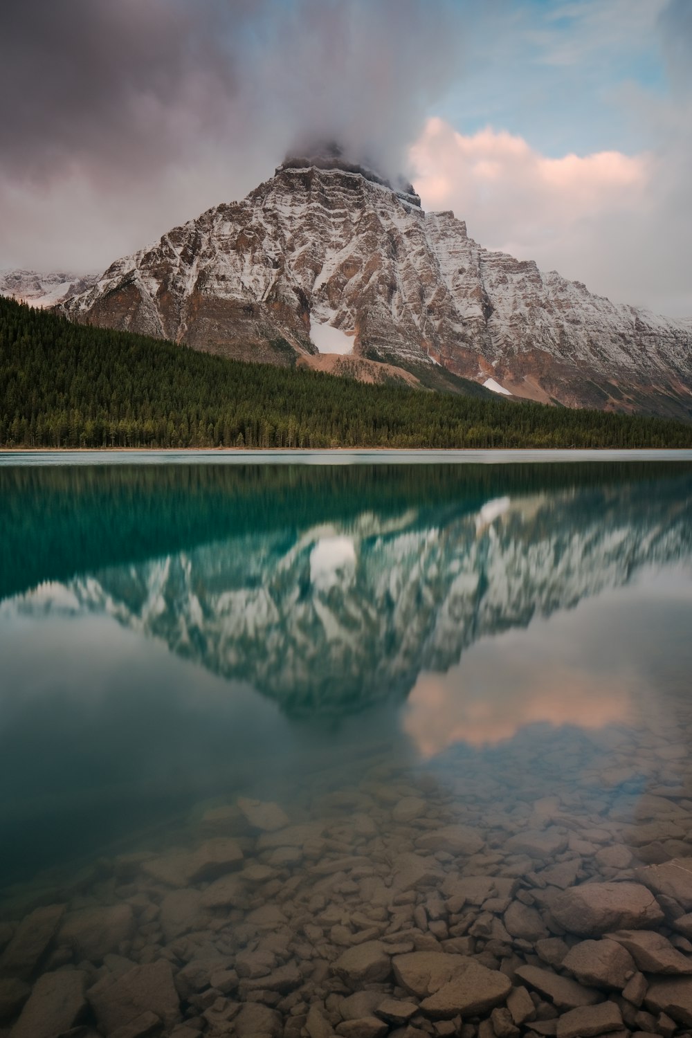 lake near mountain under white sky during daytime