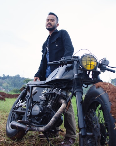 A satisfied customer standing next to a customized motorcycle, smiling proudly.