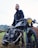 A happy customer standing next to a well-maintained motorcycle.