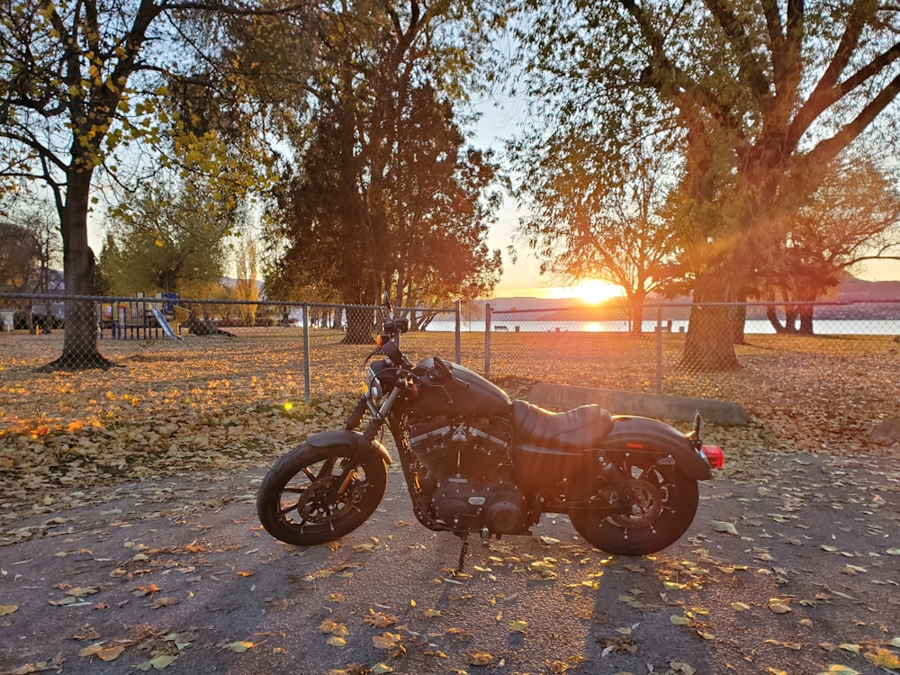 brown and black motorcycle parked on gray concrete road during sunset