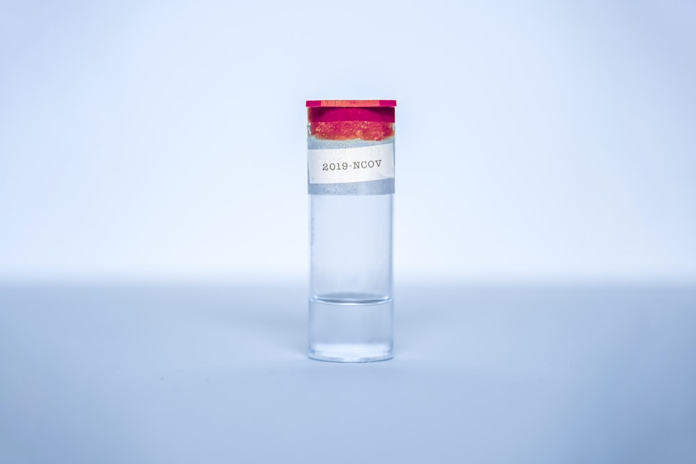 Botella de vidrio transparente con tapa roja