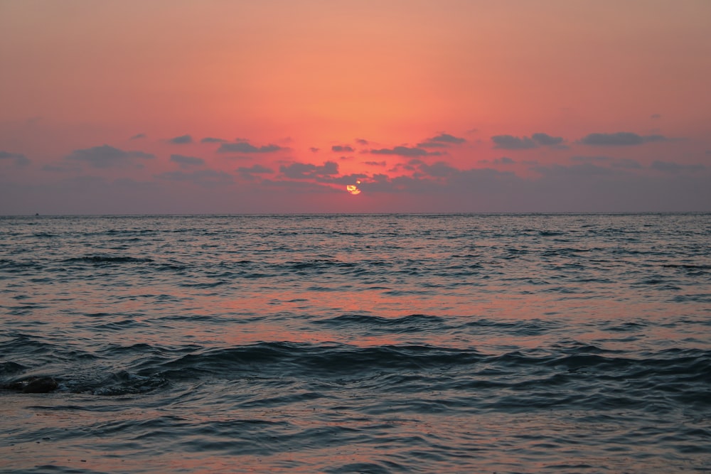 the sun is setting over the ocean with waves