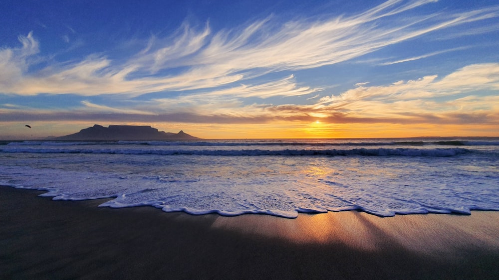 ocean waves crashing on shore during sunset