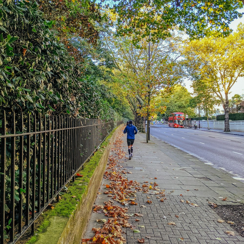 woman in blue jacket walking on sidewalk during daytime