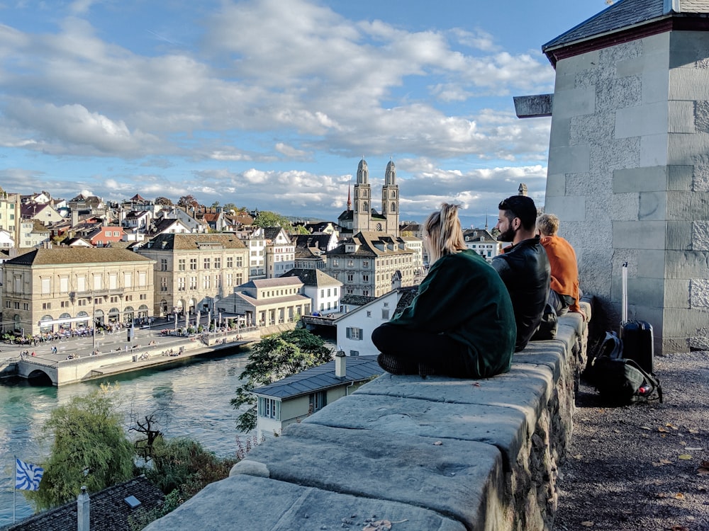 people sitting on concrete bench near body of water during daytime