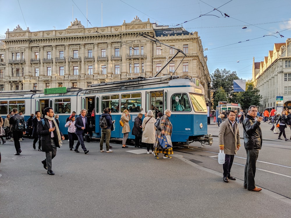Persone che camminano sulla strada vicino al tram bianco e verde durante il giorno
