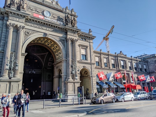 cars parked in front of white concrete building during daytime in Zürich Main Station Switzerland