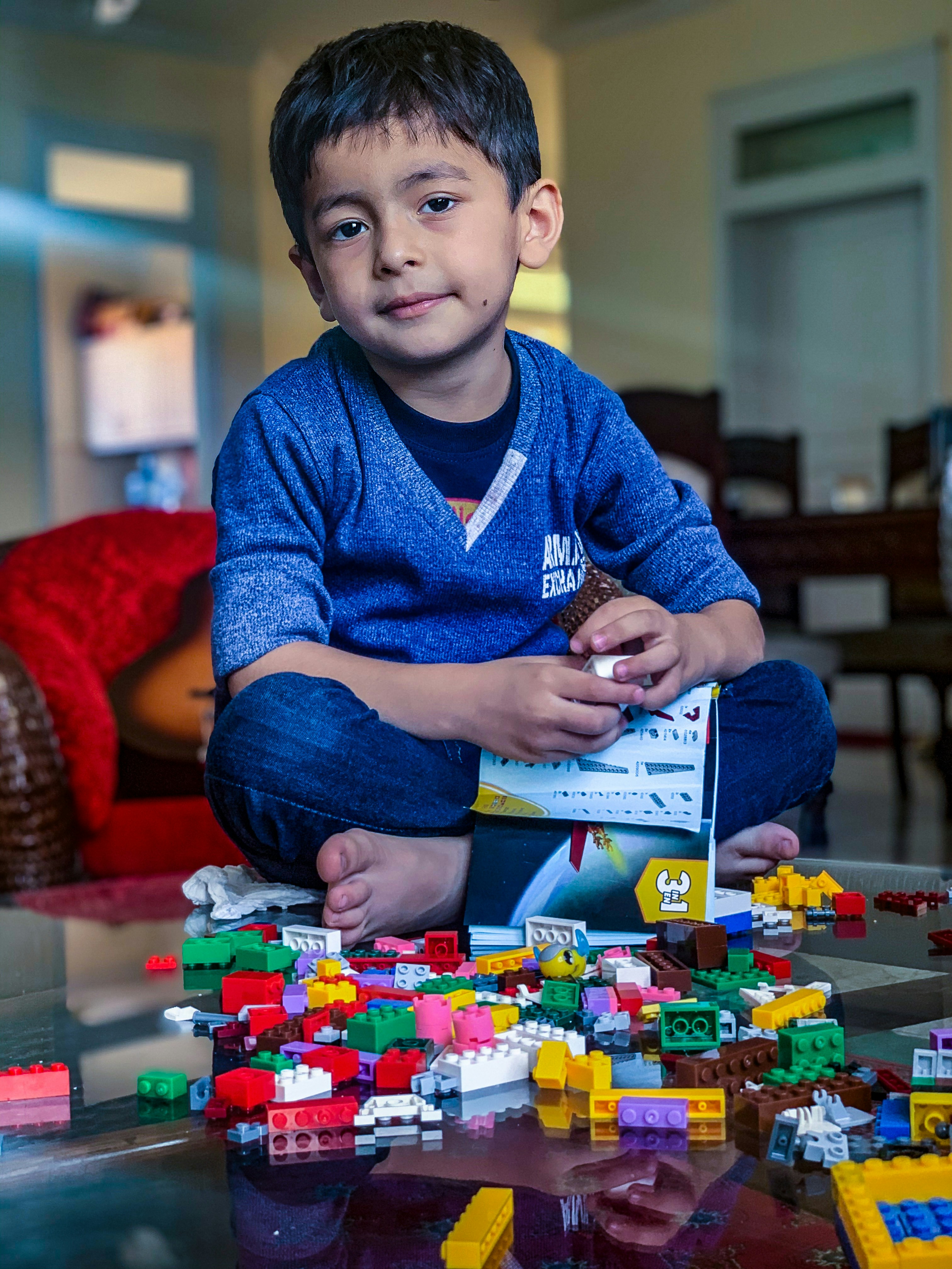 boy in blue sweater sitting on red and white checkered textile