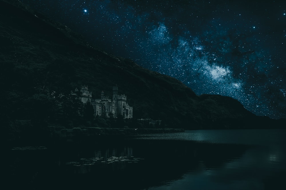 body of water near mountain during night time