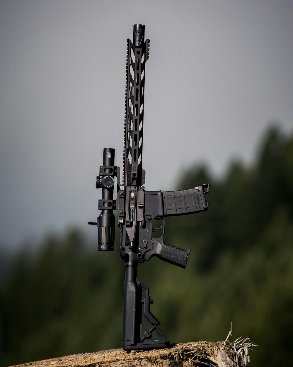 Rifle negro con mira telescópica en campo de hierba verde durante el día