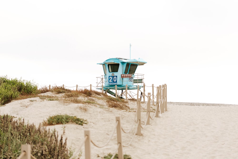 낮 동안 해변 해안에 있는 파란색 목조 인명 구조원 집