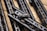 Several sleek, black metallic handguards featuring cut-out designs are arranged in a diagonal pattern on a wooden surface. A small metal component labeled 'STRIKE M MADE IN USA' is prominently attached to one of the handguards.