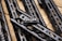 Several sleek, black metallic handguards featuring cut-out designs are arranged in a diagonal pattern on a wooden surface. A small metal component labeled 'STRIKE M MADE IN USA' is prominently attached to one of the handguards.