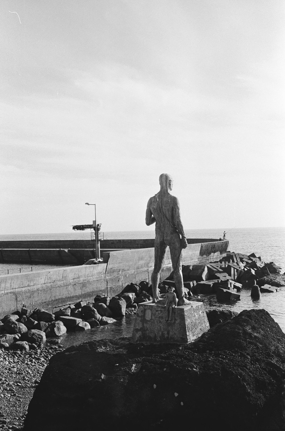 man in black suit standing on concrete wall near body of water during daytime