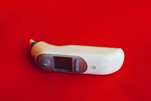 A digital thermometer resting on a clean white surface, ready for use.