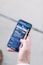A hand holding a smartphone displaying a webpage titled 'Creating a Brand' with navigation options like Home, Discovery, Members, and Topics. The background is out of focus, providing a neutral setting.