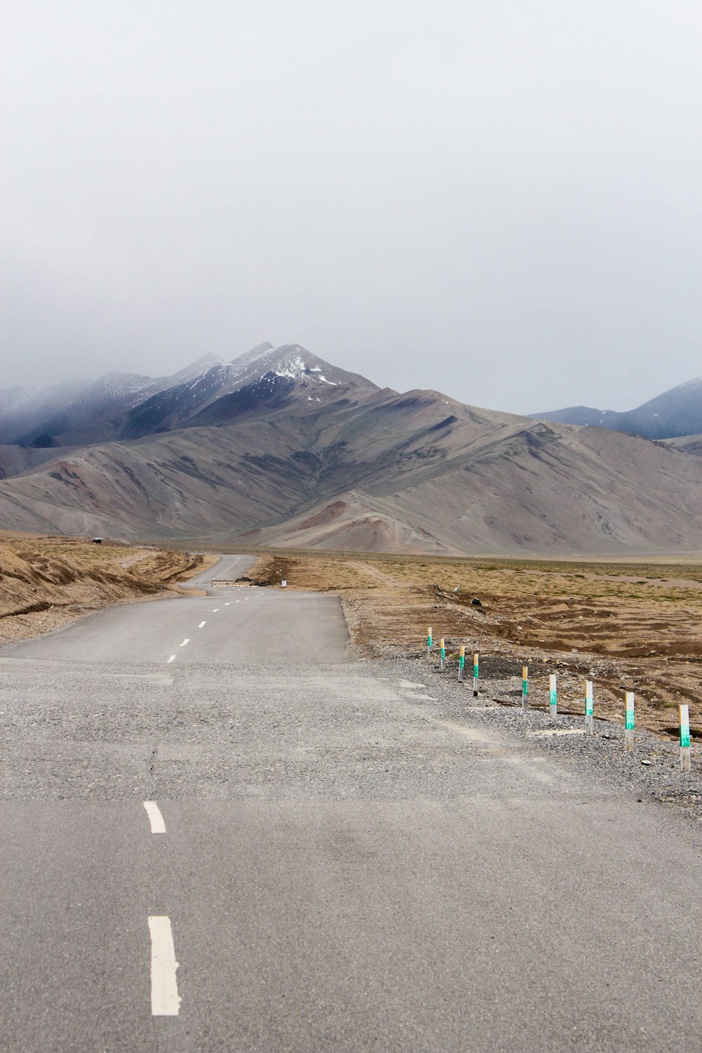 gray asphalt road near brown mountain during daytime