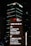 A nighttime cityscape features tall buildings, prominently displaying the logos of international banks such as HSBC and Citi, with bright lights and text guiding visitors to various locations including the HSBC Building and the Ritz-Carlton.