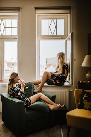 Two sisters smiling together in a cozy, inviting space filled with plants and art.