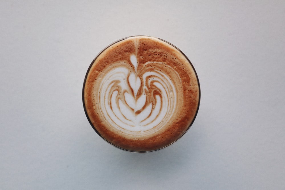 brown and white ceramic cup with heart shaped coffee