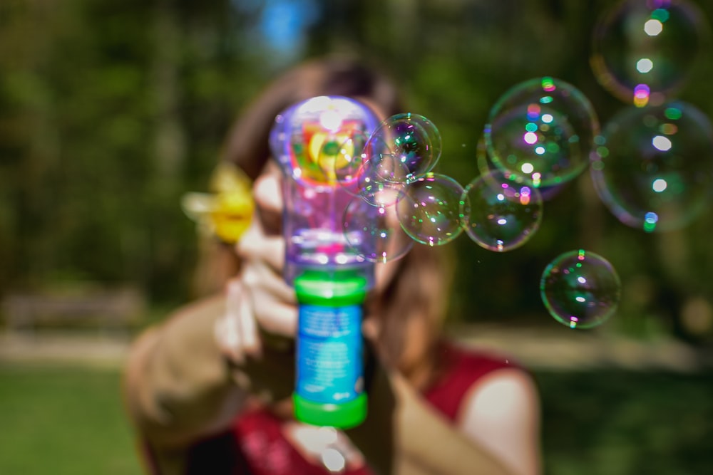 person holding green plastic bottle with bubbles