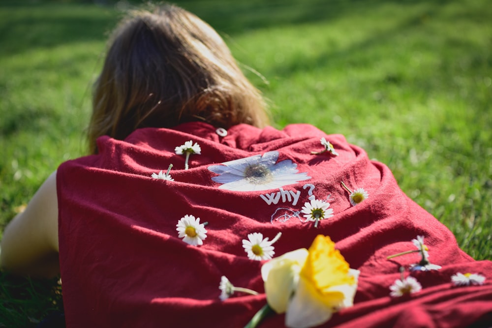 girl in red and white floral hoodie holding yellow and white flower