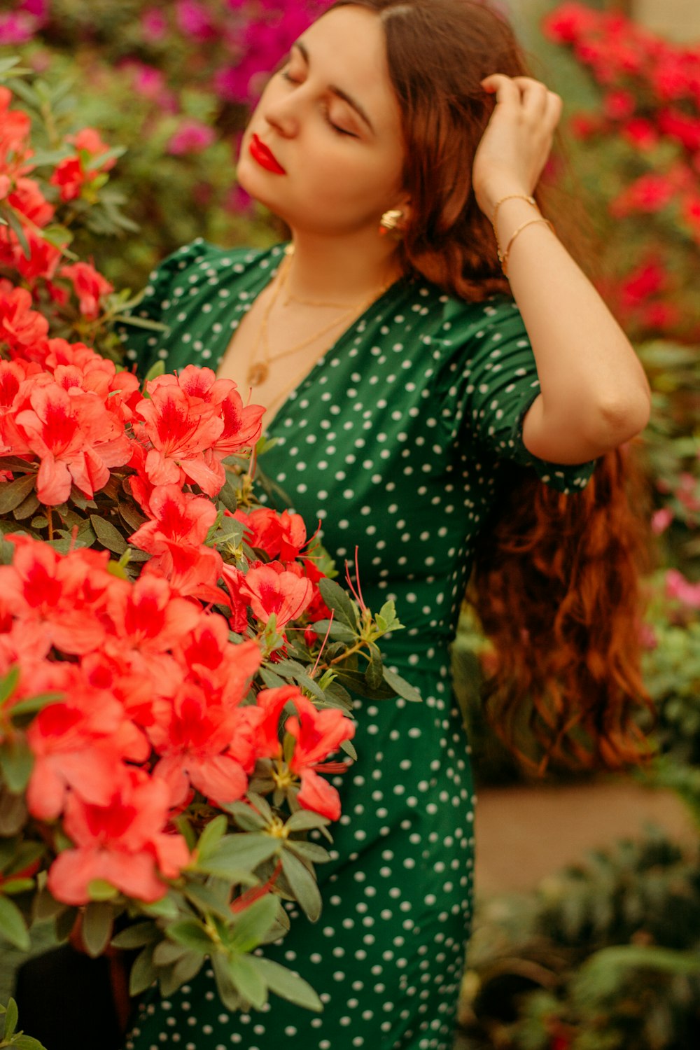 woman in green and white polka dot dress holding red flowers